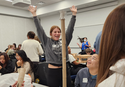 Upward Bound student Ellen Zapata celebrates the completion of the community service project. She is wearing gray sweats and has her hair pulled back in a pony tail. 