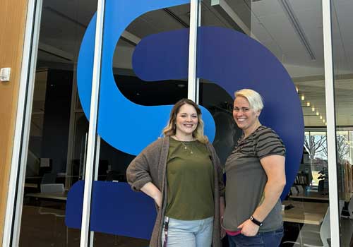 Two women smiling and posing together in front of the Southeast 