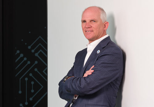 Dr. Paul Illich, President of Southeast Community College, poses with arms crossed in a professional portrait setting.