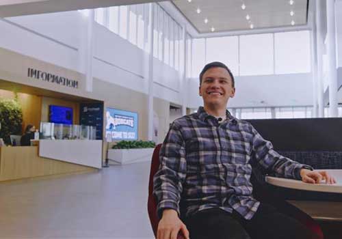Davyd Samoilenko sits in the main hall of Lincoln Campus Center, with the Information Desk in the background.