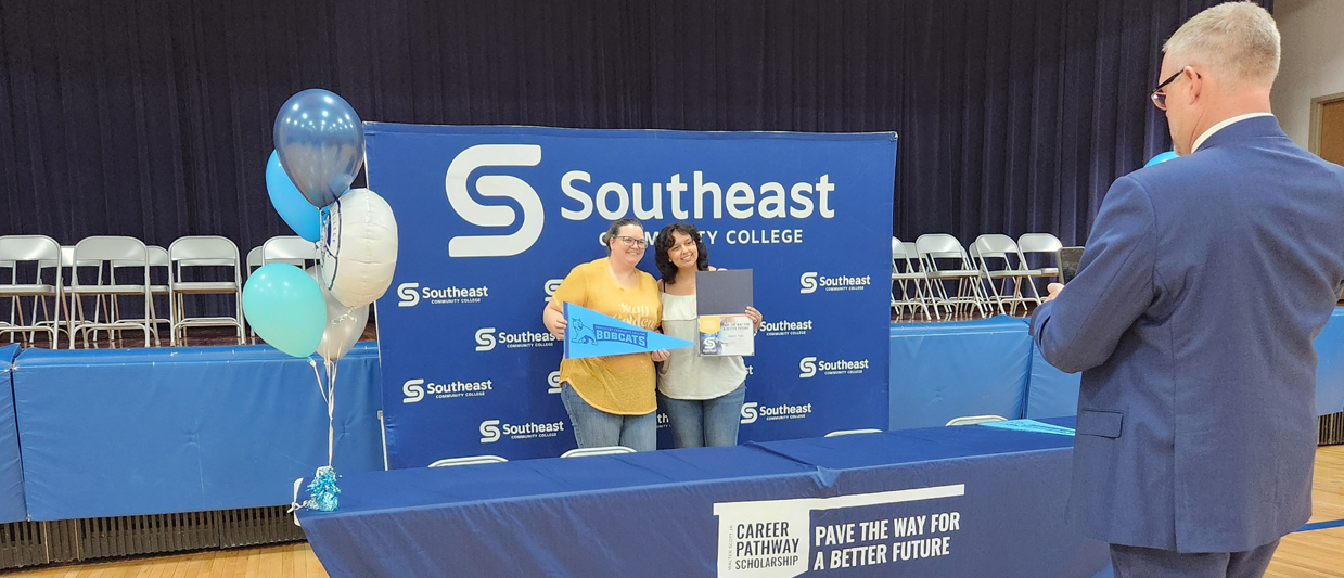 Jon Kisby, right, takes a photo of Angela Yepez and her guest at the Scott Pathway Scholarship cohort announcement. 