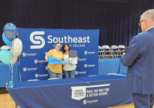 Jon Kisby, right, takes a photo of Angela Yepez and her guest at the Scott Pathway Scholarship cohort announcement.