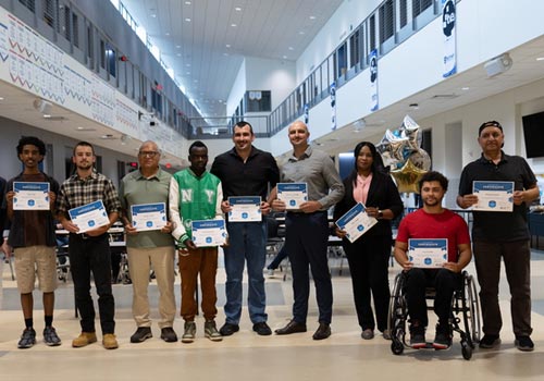 NEMAC graduates stand with their certificates in TCA