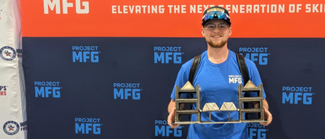 Nash Peterson stands holding a bridge he welded for the ProjectMFG National Final in San Diego