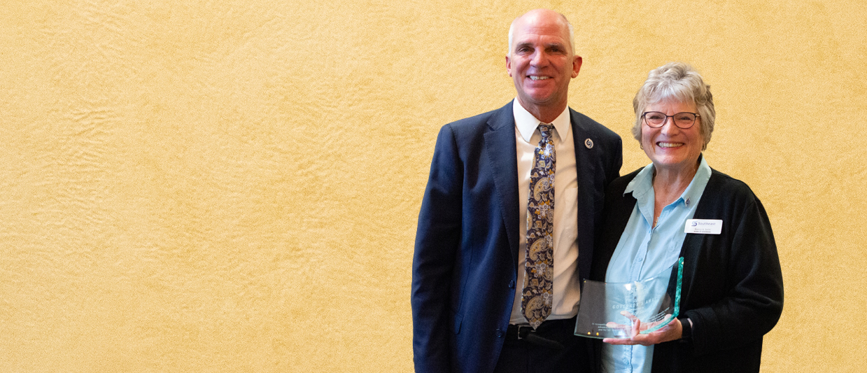 Dr. Paul Illich, SCC president, and Nancy Seim, SCC board of governors, smile as Seim holds NCCA Governors Award. 