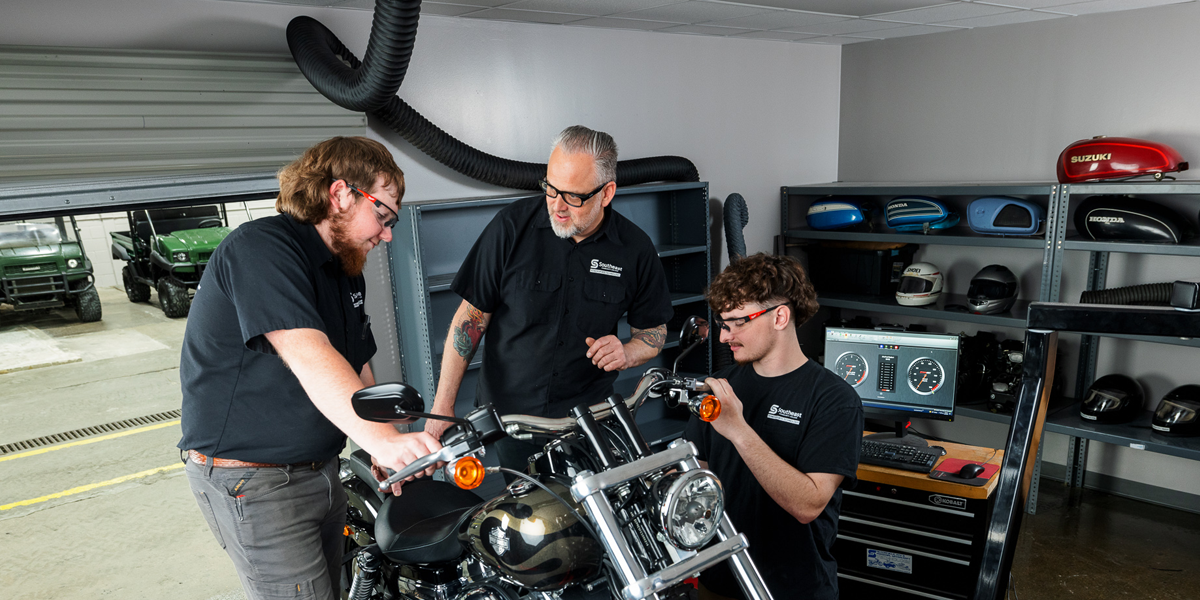 Powersports students and instructor work on a motorcycle